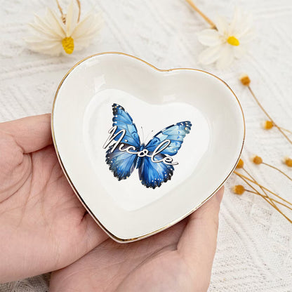 Heart-shaped trinket dish with a blue butterfly and 'Nicole' text, held in a hand with a light background.