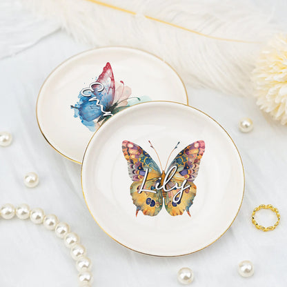 Two decorative plates with butterfly designs and the name 'Lily' on a light background with pearls and a ring.