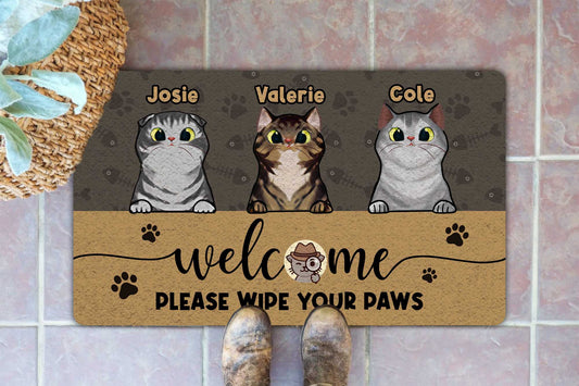 Doormat with three cat illustrations and text on a tiled floor